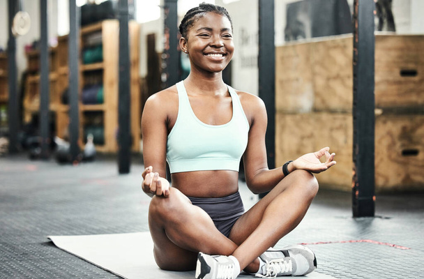 Time to bring my focus back to the present. Full length shot of an attractive young woman sitting in the gym and meditating after her workout - Fotoğraf, Görsel