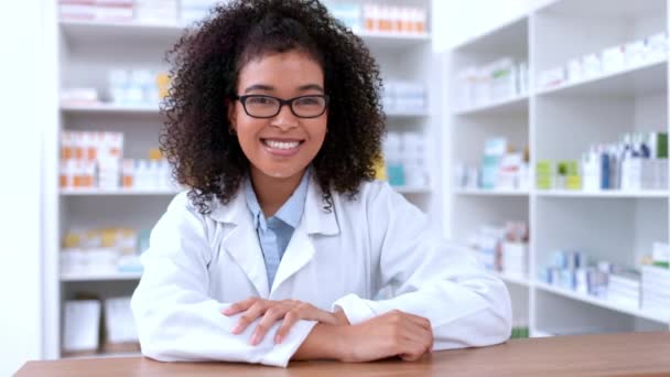 Portrait of a young pharmacist removing glasses and looking confident with her new lenses. Happy African chemist or pharmaceutical worker standing behind pharmacy prescription medicine counter. - Filmati, video