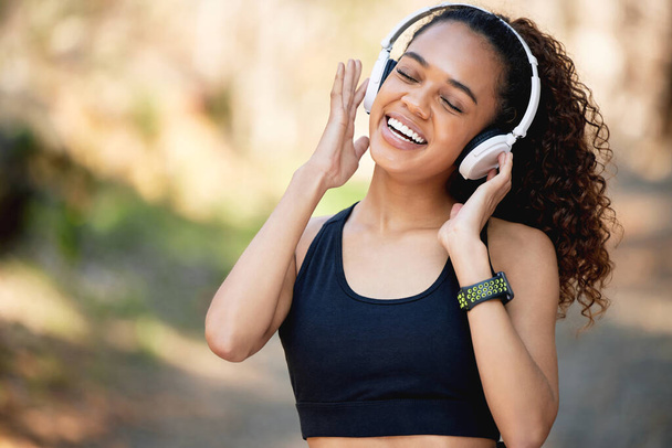 Let the music fill your soul. a young woman listening to some fun music before a run - Foto, afbeelding