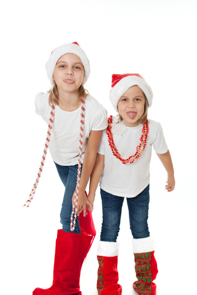 Happy sisters in santa's hats showing off tongues teasing - Foto, Bild