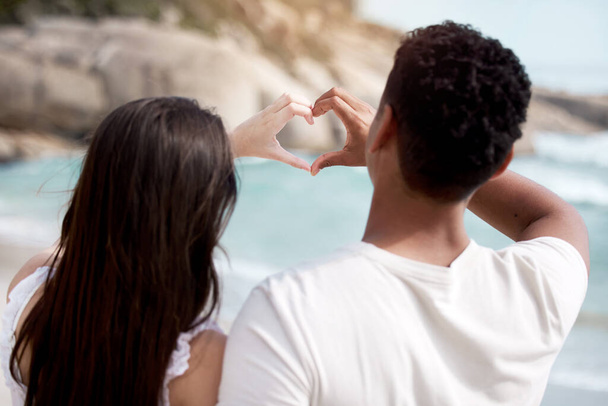 We share a love of the beach. an unrecognizable couple making a heart gesture with their hands at the beach - Foto, Imagen