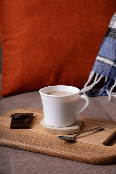 Autumn mood composition with cup of cocoa and chocolate, plaid and books on sofa background. Hot drink in autumn concept. - Fotoğraf, Görsel