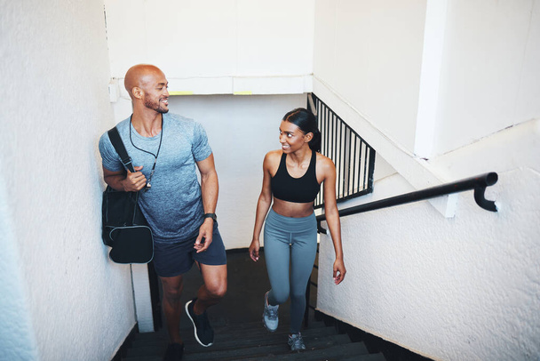 Im glad that we get to train together. a sporty young man and woman walking up a staircase together - Foto, immagini