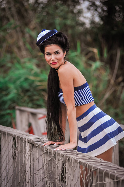 beautiful young woman in a hat and a striped dress on a background of the sea - Foto, immagini