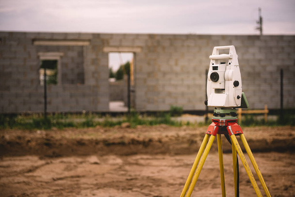 Surveyor equipment - GPS system or theodolite total positioning system outdoors at house construction site. Surveyor engineering with total station before house building - 写真・画像