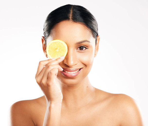 Citrus is goed voor de huid. Studio portret van een aantrekkelijke jonge vrouw poseren met een schijfje citroen tegen een grijze achtergrond - Foto, afbeelding