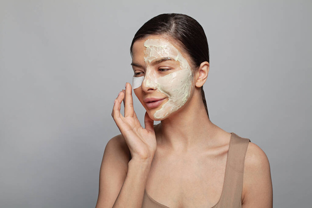 Здоровая привлекательная молодая женщина с косметической маской на коже, концепция кожи - Фото, изображение