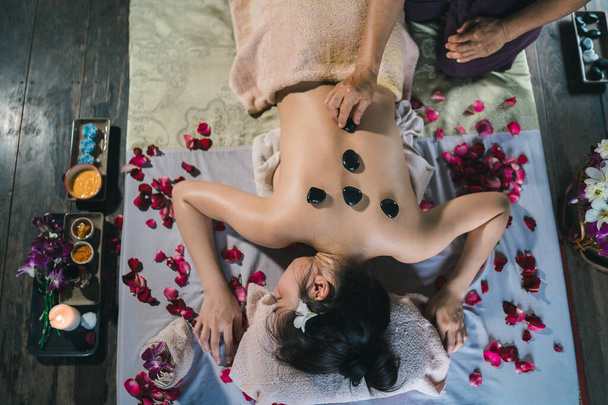 Massage and spa relaxing treatment of office syndrome using hot stone traditional thai massage style. Asain female masseuse doing massage treat back pain, arm pain, stress for woman tired from work. - Valokuva, kuva