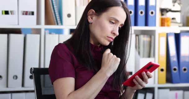 Sad young woman looks at smartphone screen. Reading bad and disturbing news concept - Video