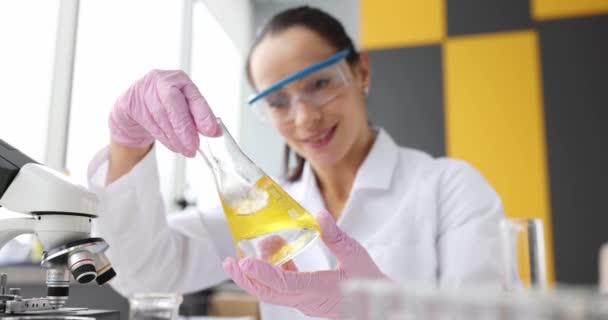 Scientist examines yellow transparent liquid in flask. Laboratory research oil concept - Footage, Video