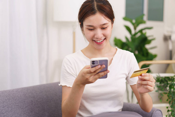 Estilo de vida en concepto de sala de estar, mujer asiática con tarjeta de crédito y el uso del teléfono para las compras en línea. - Foto, imagen