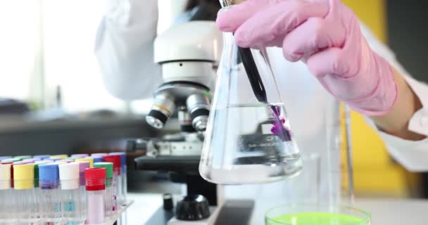 Wetenschapper in het laboratorium heeft volumetrische kolf met paarse chemische stof. Titratie concept - Video