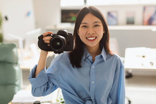 Professzionális fényképészet. Happy Chinese Female Photographer Fényképezés Holding Camera Pózol Álló Otthon. Kreatív üzlet, oktatás és karrier koncepció - Fotó, kép