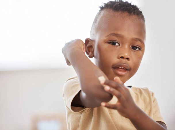 Boo boos happen, band aids help. an adorable little boy applying a bandaid to his arm - Foto, imagen