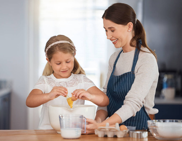 What do I do next. an adorable little girl assisting her mother while baking at home - Фото, изображение