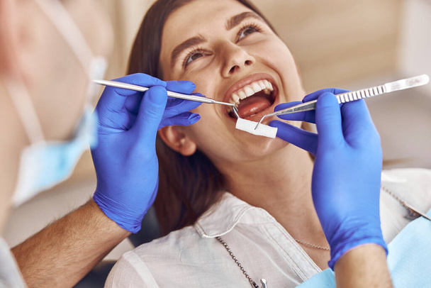 Профессиональный врач-мужчина делает анестезию счастливой пациентке в стоматологическом кабинете - Фото, изображение