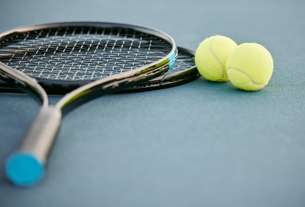 Commitment gets you gold medals. two tennis rackets and tennis balls on a court during the day - 写真・画像