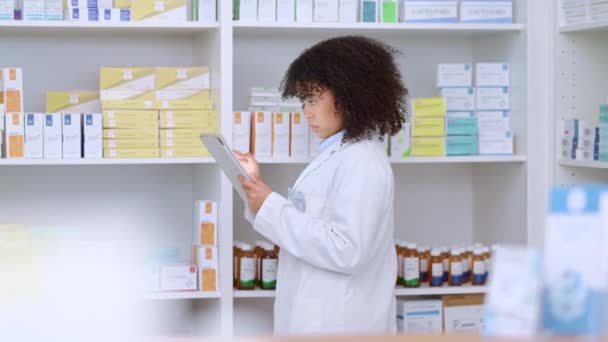 Young and focused pharmacist use her tablet to do stock taking in a modern pharmacy drugstore. Multiethnic female health professional worker or medication expert in a chemist using a digital gadget. - Metraje, vídeo