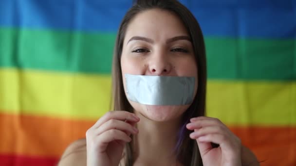 Young woman unable to speak. LGBT freedom of speech concept. Girl removing duct tape from mouth - Filmati, video