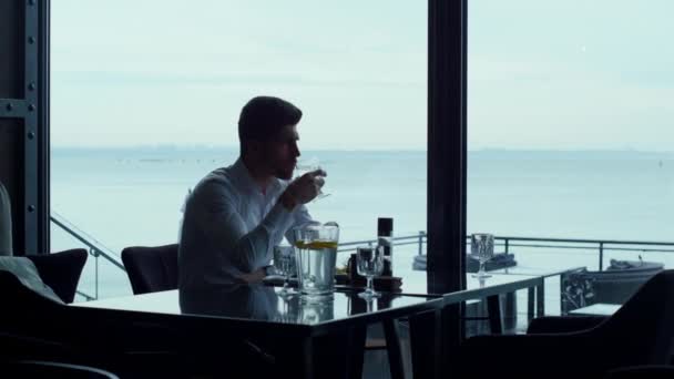 Charismatic manager resting lunch in restaurant. Attractive freelancer man silhouette spending breakfast in cozy hotel bar. Relaxed businessman drinking water glass in cafe. Wealthy lifestyle concept. - Πλάνα, βίντεο