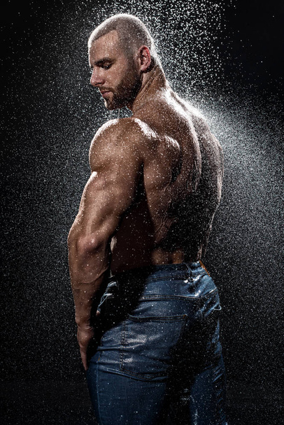 Muscular man under the rain in studio. Sexy male in water drops - Valokuva, kuva