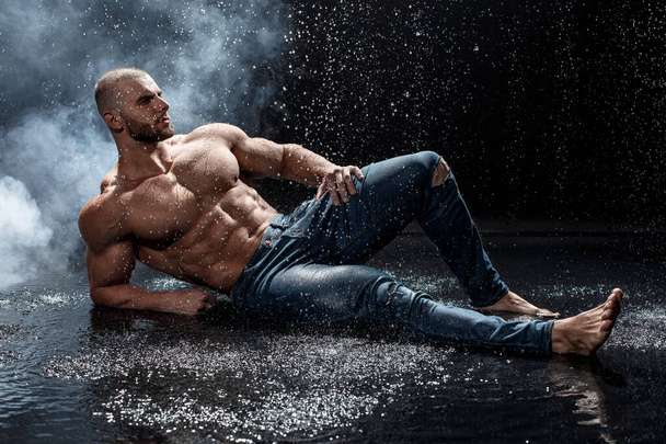 Muscular man under the rain in studio. Sexy male in water drops, abs - Photo, Image