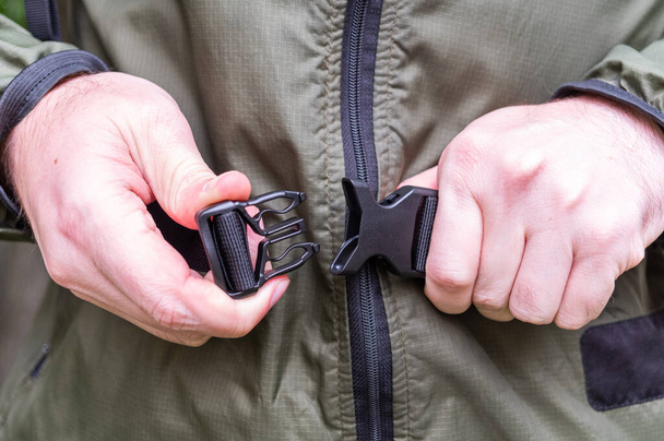 Fasten the waist belt of the backpack. Connect the latch with both hands. Connect the lock with your hands. Front view. - Photo, image