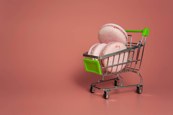 pink macaroon in a grocery cart on a pink background - Photo, image