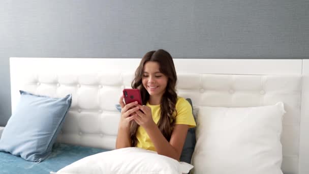 happy child texting on mobile phone in bedroom, online shopping. - Filmagem, Vídeo