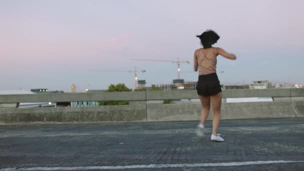 Young woman dances alone on empty street. Stylish and funky dancer performs freestyle in a deserted urban environment. Hip hop artist practicing her moves and enjoying a wild and free lifestyle. - Filmati, video
