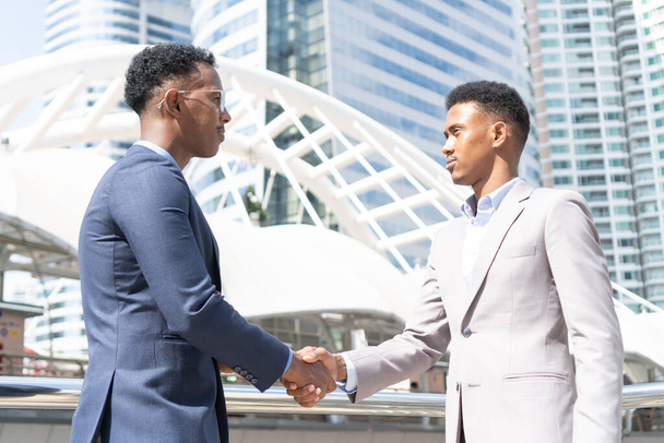 Welcome to our team. young modern men in smart casual wear shaking hands. Two smiling businessmen shaking hands together. Two confident businessmen shaking hands at the outside of the office. - Foto, afbeelding