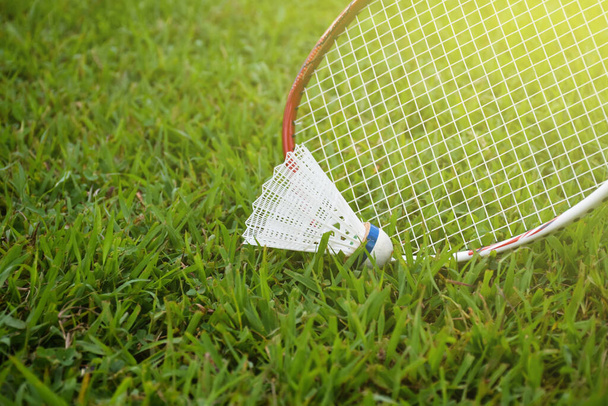 Picking up the badminton shuttlecock on grasslawn by using badminton racket, soft and selective focus on racket and shuttlecock, outdoor badminton playing concept. - Foto, Bild