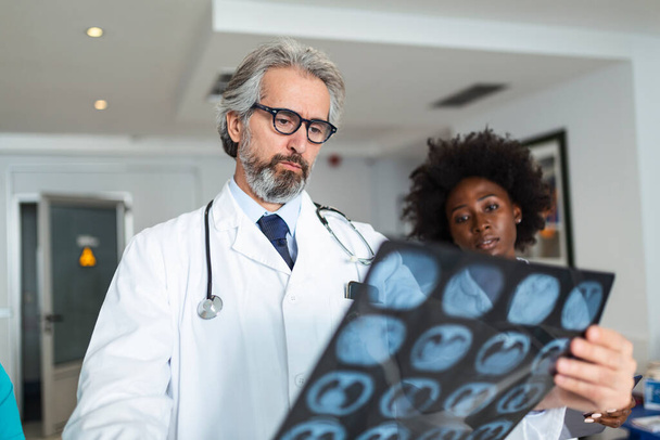 Equipa de profissionais de saúde que examinam a radiografia dos pulmões do doente. Médico masculino e feminino olhando para os pulmões raio-x no hospital durante a pandemia de covid19 - Foto, Imagem