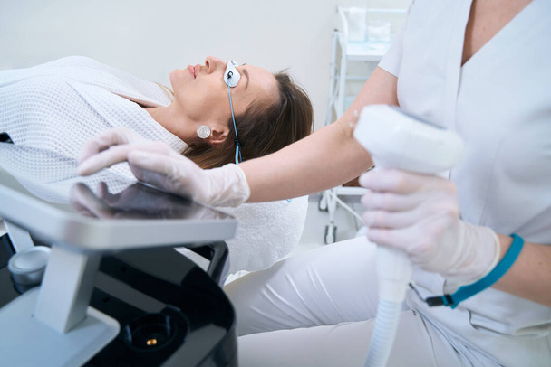 Cropped photo of doctor using skin rejuvenation machine with monitor - Foto, imagen