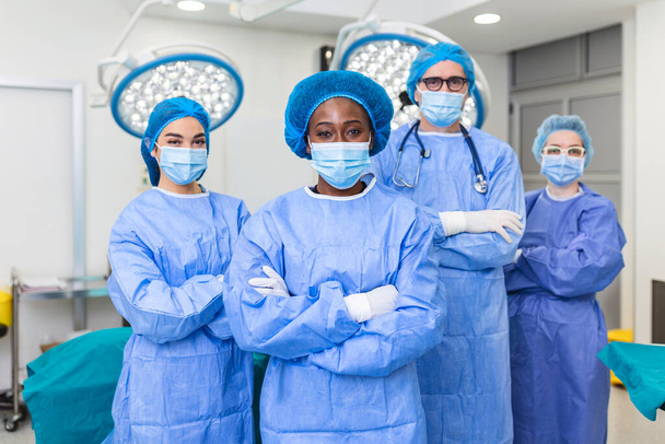 Group of medical surgeons wearing hospital scrubs in operating theatre. Portrait of successful medical workers in surgical uniform in operation theater, ready for next operation. - Fotografie, Obrázek