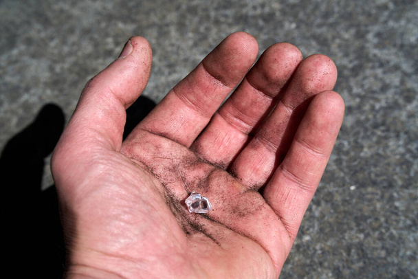 Рука с имитированным бриллиантом, притворяющимся найденным на земле. Высокое качество фото - Фото, изображение