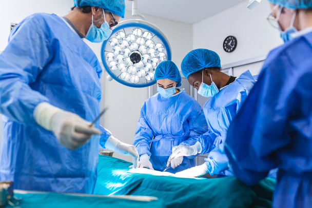 Χειρουργοί εκτελούν επιχειρήσεις στο θέατρο επιχειρήσεων. χειρουργική επέμβαση αύξησης στήθους στο χειρουργικό εμφύτευμα εργαλείων χειρουργού χειρουργείου. Έννοια ιατρικής περίθαλψης. - Φωτογραφία, εικόνα