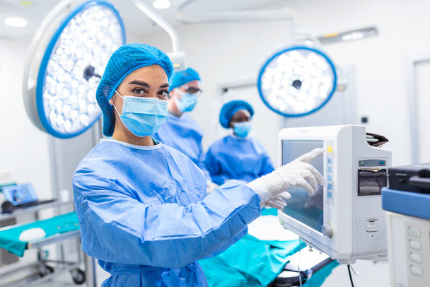 Різна команда професійних хірургів здійснює інвазивну хірургію на пацієнта в операційній кімнаті лікарні. Медсестра розносить інструменти хірургу, анестезіологу моніторам. - Фото, зображення