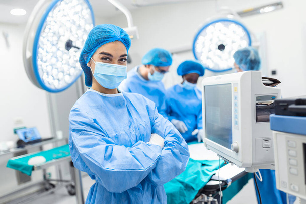 Anesthesiologist keeping track of vital functions of the body during cardiac surgery. Surgeon looking at camera. Doctor checking monitor for patient health status. - Foto, Imagem