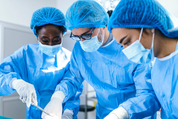 A surgeon's team in uniform performs an operation on a patient at a cardiac surgery clinic. Modern medicine, a professional team of surgeons, health. - Zdjęcie, obraz