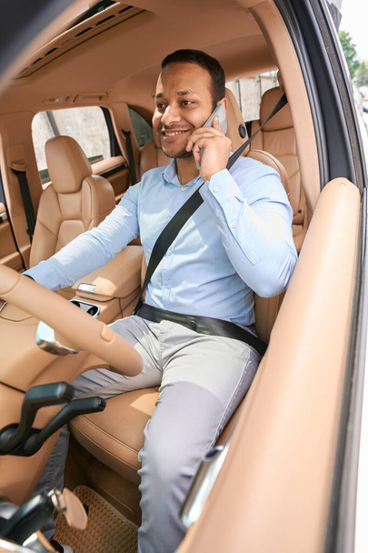 Smiling happy young male entrepreneur driving his motor vehicle during phone conversation - Foto, Bild