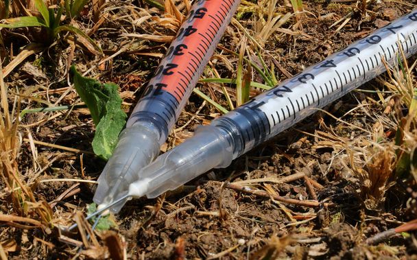 two abandoned syringes used by drug addicts left on the ground on the public park after use - Φωτογραφία, εικόνα