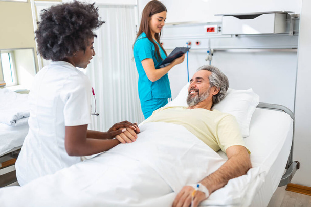 Healthcare concept of professional doctor consulting and comforting elderly patient in hospital bed or counsel diagnosis health. Medical doctor or nurse holding senior patient's hands and comforting him - Fotó, kép