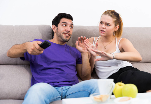Young upset woman trying to take away TV remote from her boyfriend - Fotografie, Obrázek