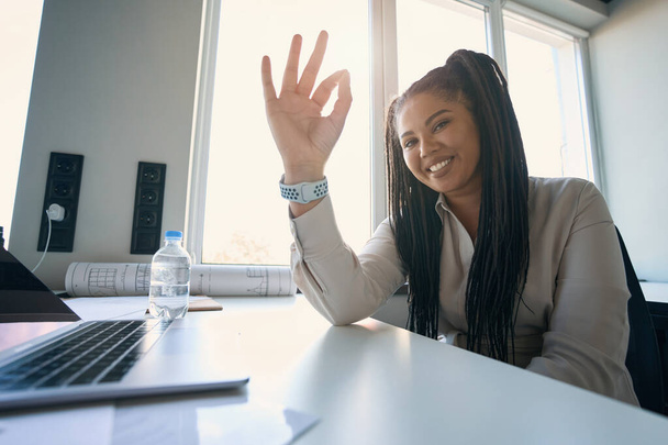 Smiling cheerful female engineer sitting at office table and making OK gesture - Foto, Bild