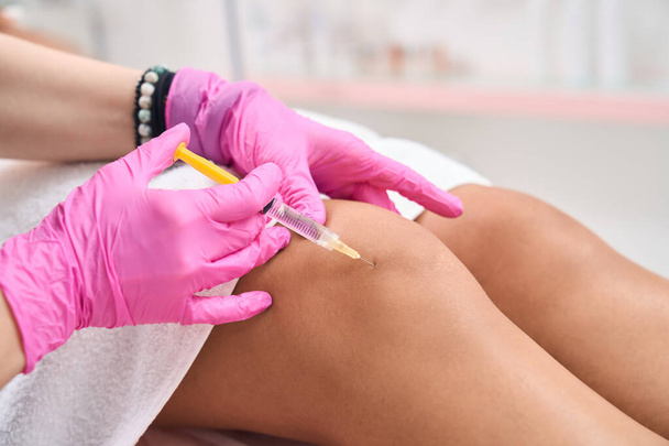 Rejuvenating injections of hyaluronic acid in the knee area are performed at the aesthetic cosmetology clinic - Foto, Bild