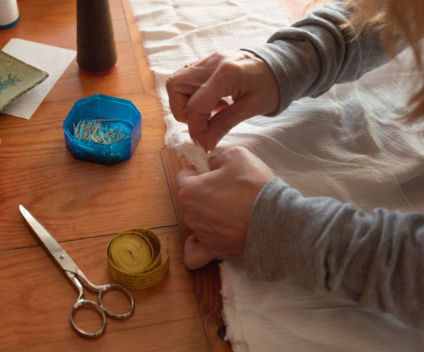 A female carefully sewing white cloth - Foto, Bild