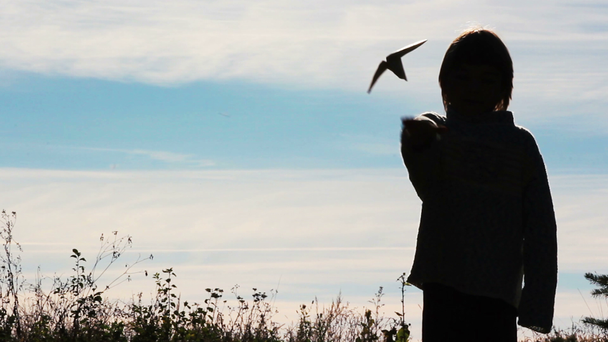 Silhueta de um menino brincando com um avião de papel.Menino solitário brincando ao ar livre.A criança começa avião no fundo do céu
. - Filmagem, Vídeo