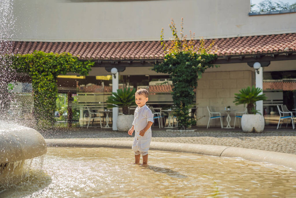 Happy boy plays in the street fountain. - Foto, Bild