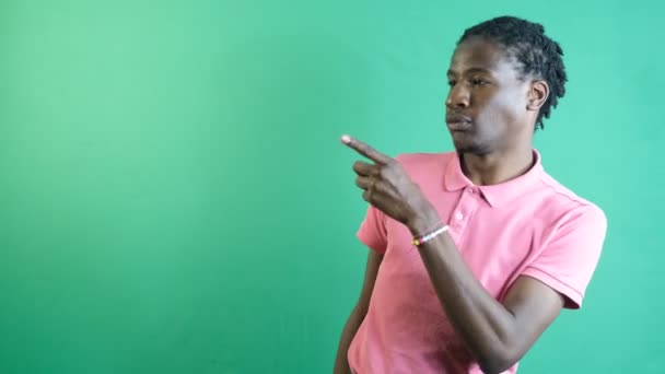 Man points corner of screen, black teenager pointing to the corner side of the screen with his left hand, show body language and facial expressions in front of a green screen - Metraje, vídeo